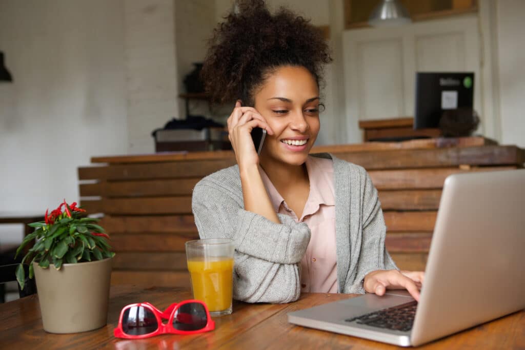 Woman making a phone call while using her laptop computer