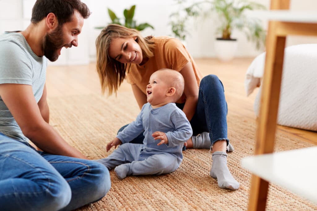Happy Family Sitting On The Floor With Baby