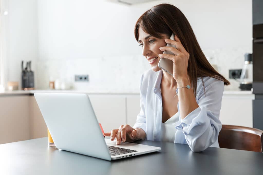 Woman on laptop computer while making a phone call