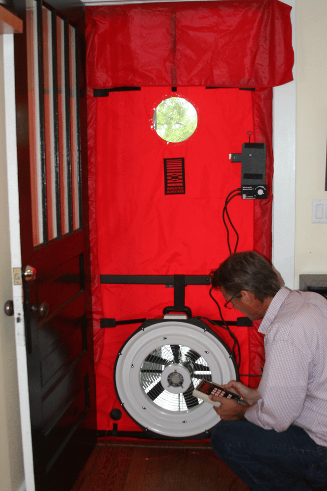 William kneeling while performing blower door test