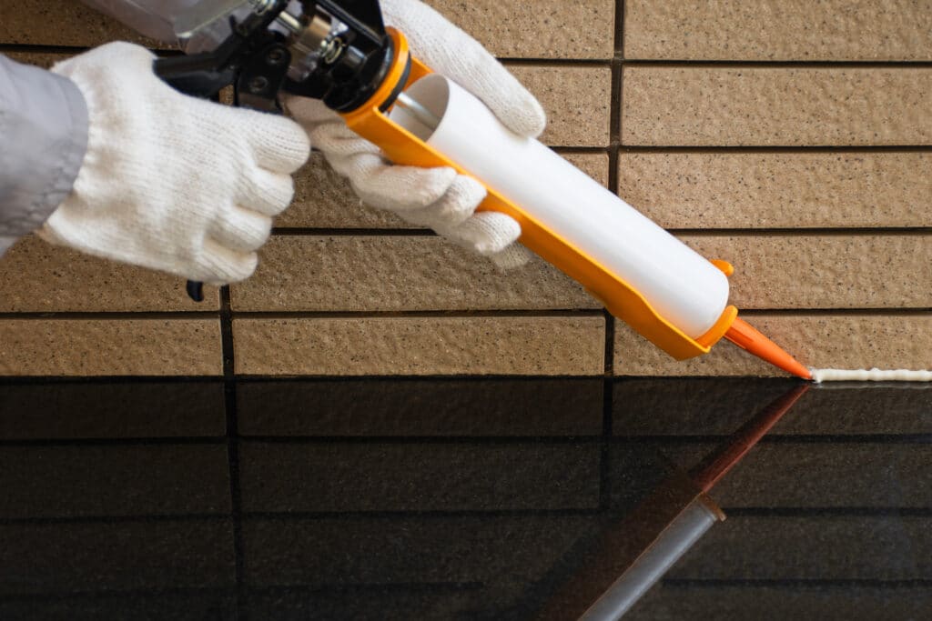 Hands using a caulk gun to apply caulk for air sealing