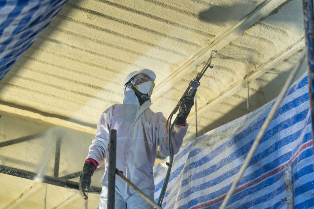 Worker applying spray foam insulation in commercial building